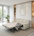 Sofa 3-osobowa, skórzana, z rozłożoną funkcją spania w kolorze jasny beż na tle eleganckiego salonu.