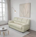 Sofa 3-osobowa, skórzana, z funkcją spania w kolorze jasny beż na tle eleganckiego salonu.